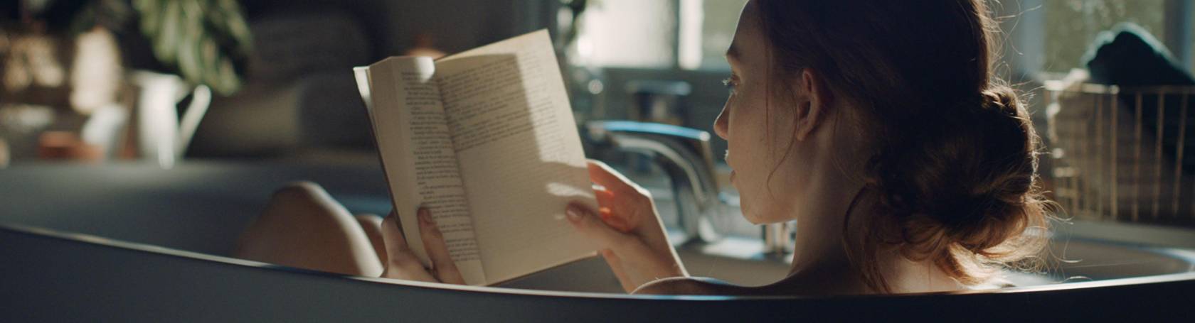 Woman reading a book and having a bath